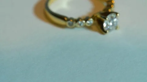 Gold Ring with Diamond Rotating around into focus on white surface Video stock 70244446