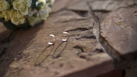 Gold ring lie on the stone surface in sunny day Vidéo 123783501