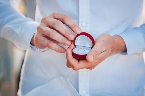 A gold ring in a red box in the hands of a guy Stock Photos