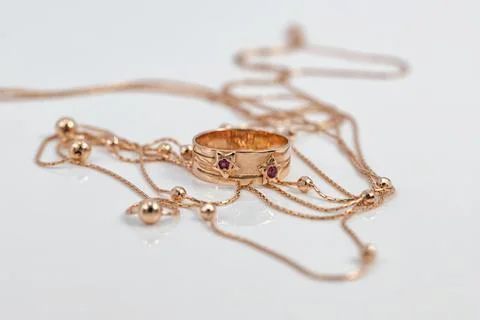 A gold ring with ruby inserts in the shape of stars and a gold chain with bal Stock Photos