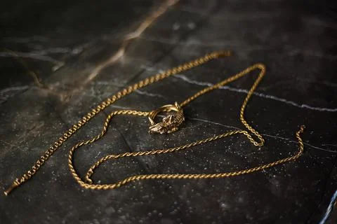 Gold ring in the shape of a crocodile with a gold chain on a dark background Stock Photos