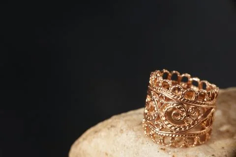A gold ring on a stone. Black background with copy space. Stock Photos