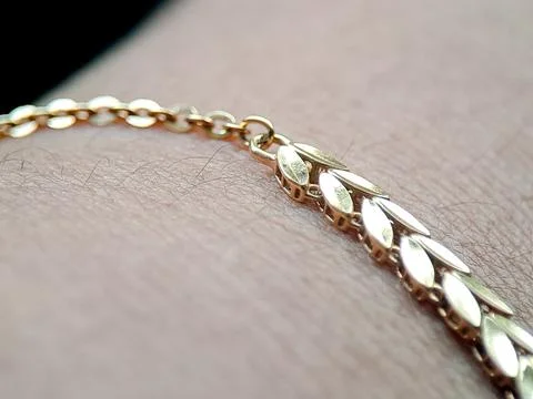 Gold ring worn on a finger, featuring leaf-shaped links, photographed indoo.. Stock Photos