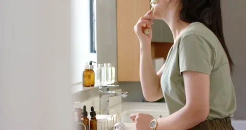 Gold roller is being placed at chin and rolling upward along jawline at vanity, Stock Footage 336716147
