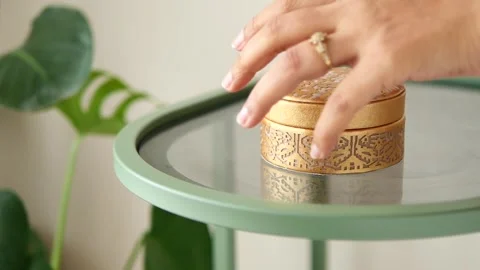 Gold round box on glass table with green plant Stock Footage 339755603