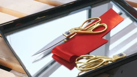 Gold scissors and red satin ribbon on a mirror surface in a sunlit room. A setup Stock Footage 312016124