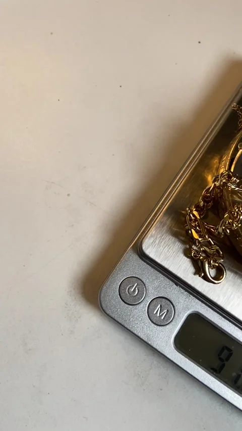 Gold scrap pile chains and gold bangle  jewelry on scales to be weighed at pawn  Stock Footage 151341199
