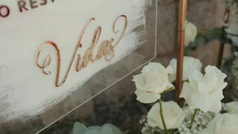 Gold Script Lettering on Acrylic Wedding Sign with White Roses Close Up Video stock 343697694