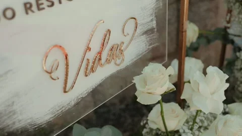 Gold Script Lettering on Acrylic Welcome Sign Beside White Roses at a Ceremony Video stock 343697669