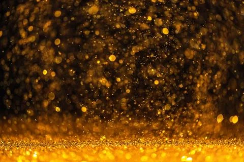 Gold sequins fall on a black background Stock Photos