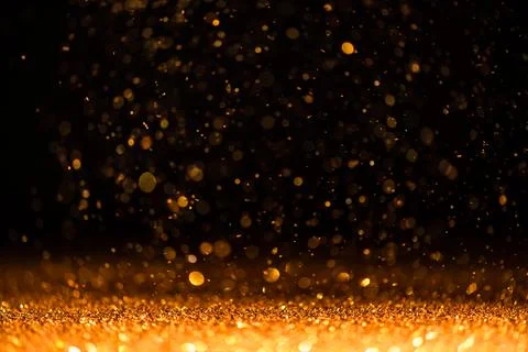 Gold sequins fall on a black background Stock Photos