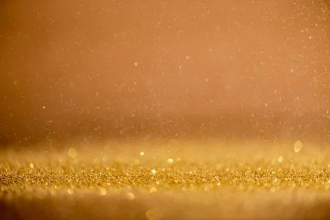Gold sequins fall on a black background Stock Photos