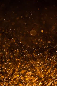 Gold sequins fall on a black background Stock Photos