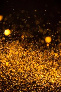 Gold sequins fall on a black background Stock Photos