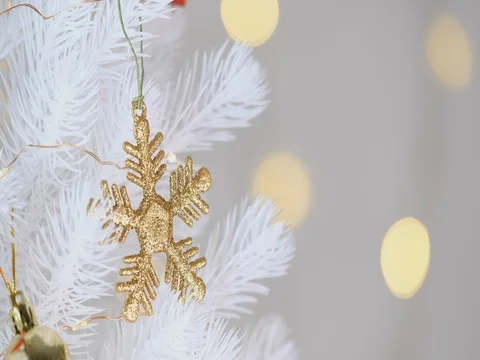 Gold snowflake and decor ball hanging on white Christmas tree with bokeh lights Stock Footage