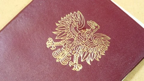 Gold uncrowned Polish eagle emblem on a burgundy official document cover, a.. Stock Footage 339372746