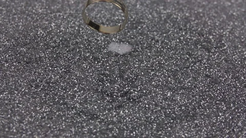 Gold wedding ring falls on silver sequins. Slow motion 500 fps. Stock Footage 155415004