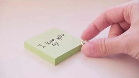 Gold wedding ring lying next to the I love you note on the yellow sticker. Stock Footage 335116666