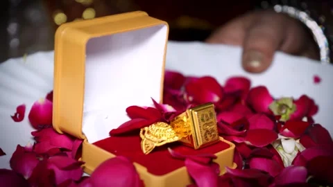 Gold Wedding Ring Placed on Rose Petals During Hindu Ritual 스톡 동영상 329384494