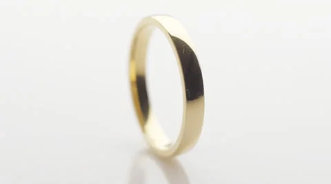 Gold wedding ring turning on white Stock Footage