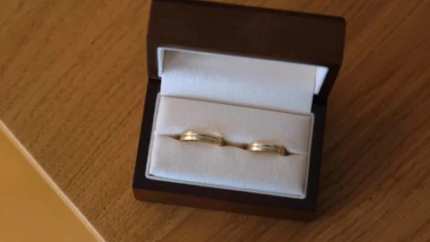 Gold Wedding Rings Displayed in Open Jewelry Box on Wooden Table Stock Footage 342022684