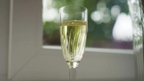 Gold wedding rings fall into a glass of champagne. Slow motion Stock Footage 233525655