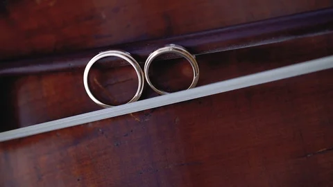 Gold Wedding Rings macro closeup on bow for violin on a musical instrument 動画素材 114492964