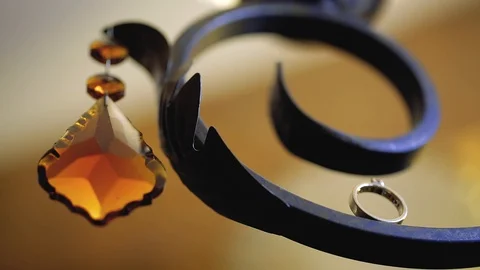 Gold Wedding Rings macro closeup lensflare on an iron forged lamp with crystal Stock Footage 114495117