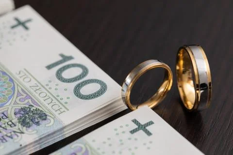 Gold wedding rings surrounded by a stack of Polish banknotes. Stock-Fotos