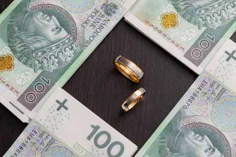 Gold wedding rings surrounded by a stack of Polish banknotes. 写真素材