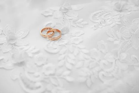 Gold wedding rings on white dress Stock Photos
