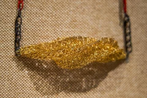 Gold wire braided feather shaped pendant exhibit Stock Photos