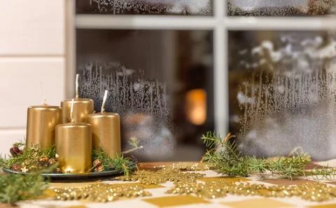 Golden Advent candles on a table in front of a window in winter weather, ho.. Stock Photos