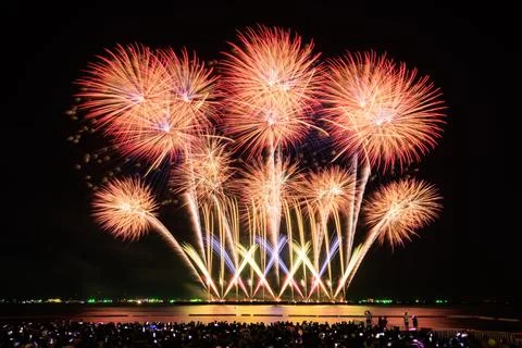 Golden And Red Fireworks Exploding Over Dark Ocean And Beach Crowd At Night.. Stock Photos