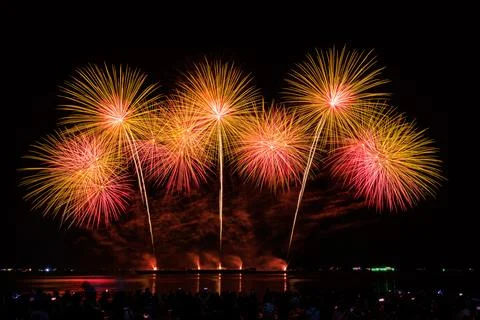 Golden And Red Fireworks Exploding Over The Sea Before Crowd At Night Long .. Foto stock