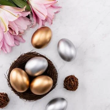 Golden and silver Easter eggs in the nest with pink Double Lily flower. 스톡 사진