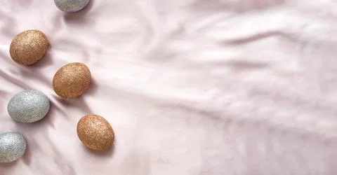 Golden and silver glitter Easter eggs on a pink and coral background 写真素材