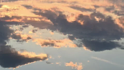 Golden backlit sunset clouds reflecting in rippling lake water, slow motion Stock Footage 338238142