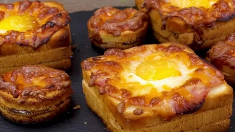 Golden baked egg and ham sandwiches with melted mozzarella cheese on black plate Stock Footage 324943330