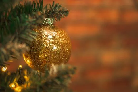 Golden ball in glitter hanging on the Christmas tree Stock Photos