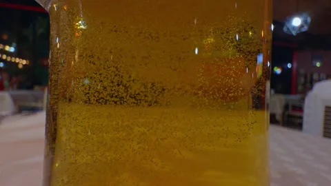 Golden Beer Bubbles Rise Inside a Clear Glass at a Restaurant Table, Showing Ref Stock Footage 341979339