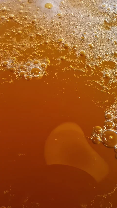 Golden beer surface with frothy bubbles seen in extreme close-up macro detail Stock Footage 336717944
