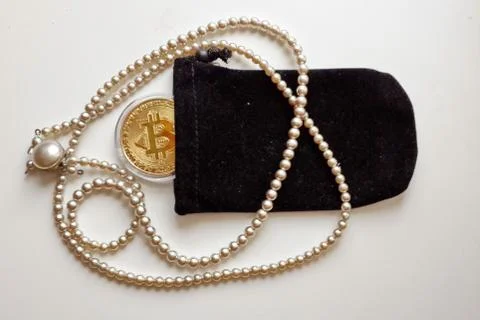 Golden Bitcoin coin, black velvet sac and pearl necklace Stock Photos