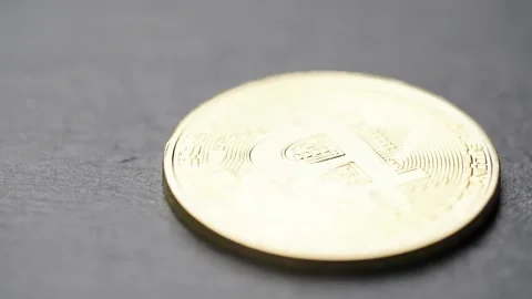 Golden Bitcoin coin on a dark surface representing digital currency and Stock Footage 302193775