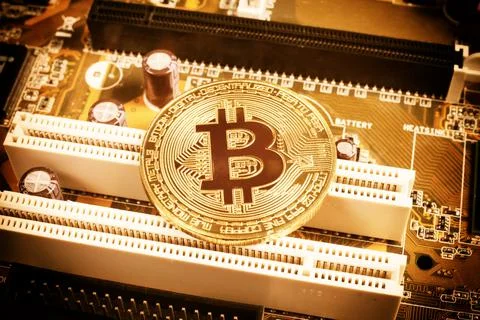 Golden bitcoin on a computer board, close-up, tinted orange, top view Stock Photos