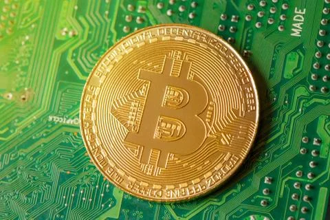 Golden Bitcoin Cryptocurrency on computer circuit board. Macro shot Stock Photos