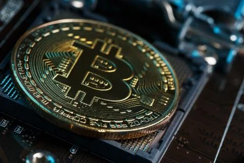 Golden Bitcoin Cryptocurrency on computer circuit board CPU. Macro shot. Stock Photos