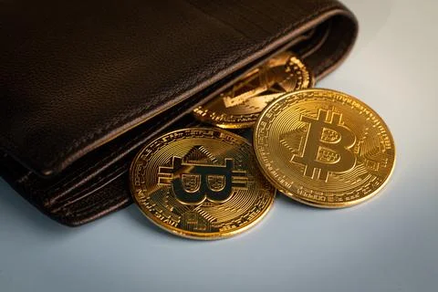 Golden Bitcoin token falling out of a wallet. Stock Photos