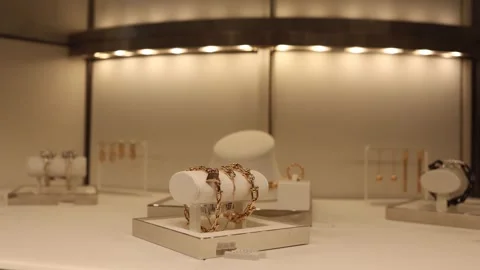 Golden bracelets with lock design and elegant earrings displayed in luxury jewel Stock Footage 315414538