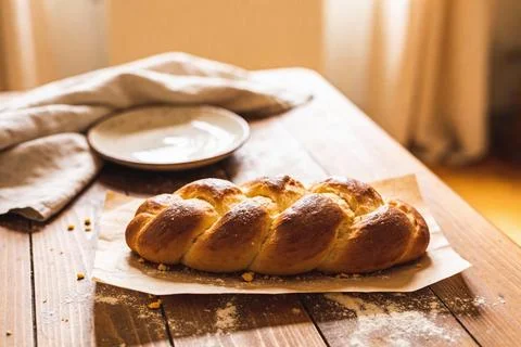 Golden braided challah bread on a rustic wooden table with a linen napkin a.. Stock Photos